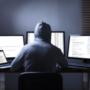 Rear,View,Of,A,Hacker,Using,Multiple,Computers,For,Stealing